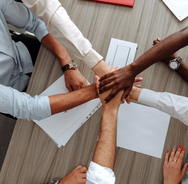 people sitting at a table and putting their hands together in the middle