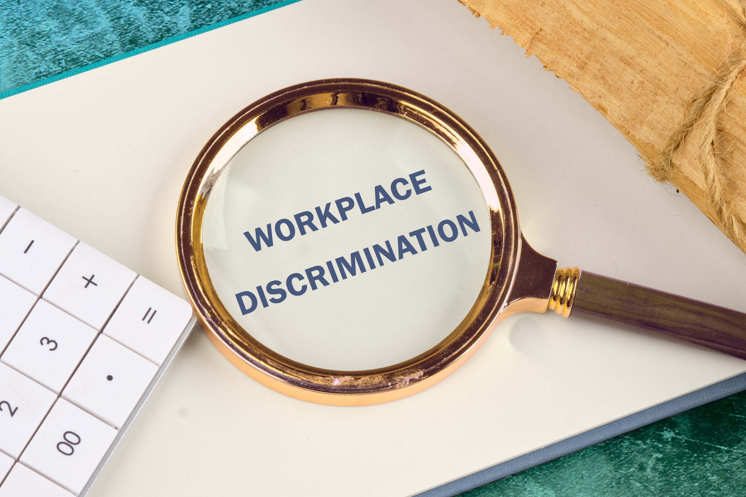 magnifying glass focusing on a page over the words "workplace discrimination"