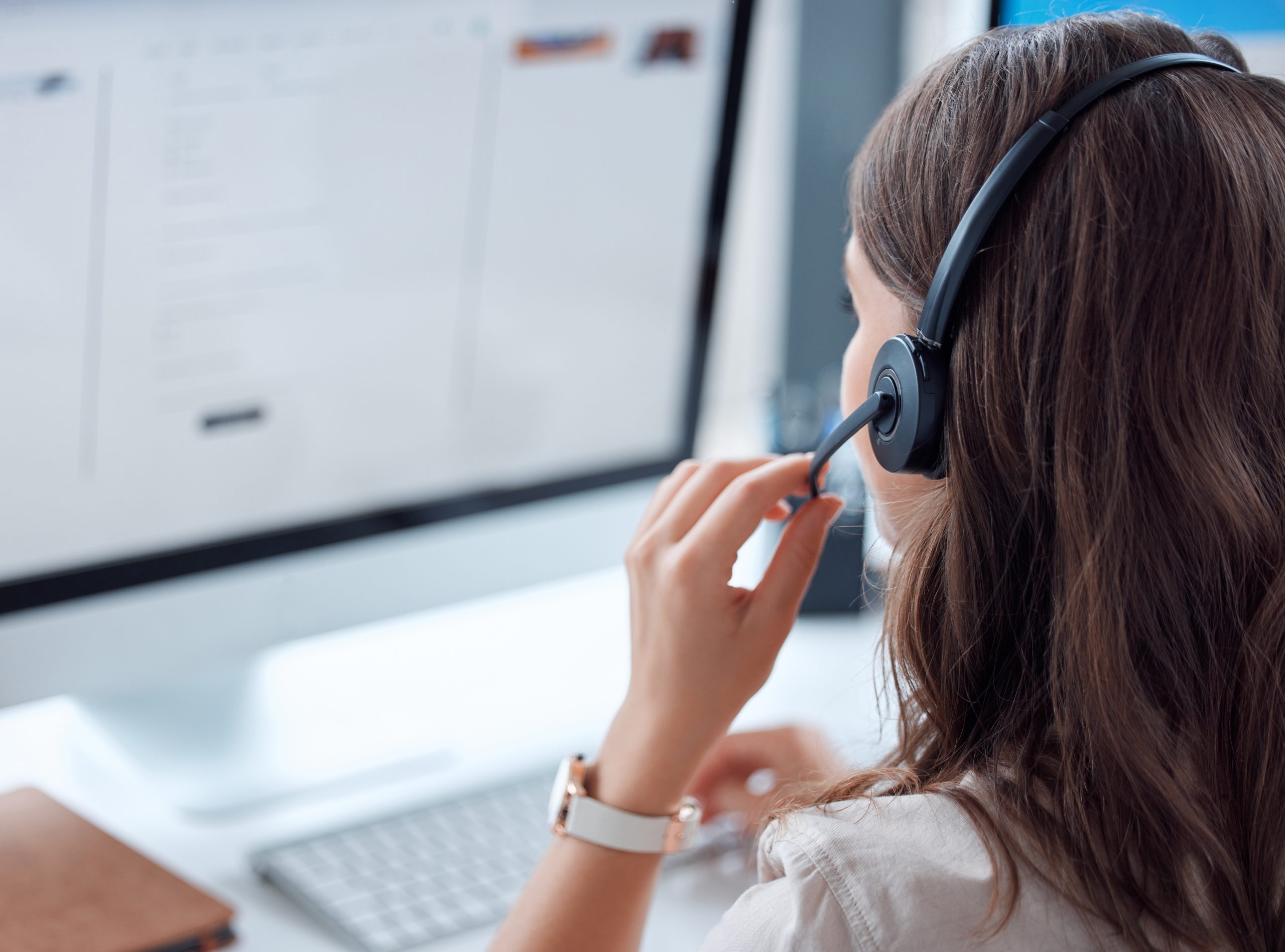 over the shoulder view of an employee with headset looking at her computer screen